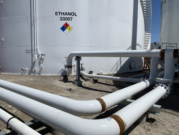 View of piping at a Chemical plant with an Ethanol tank in the background